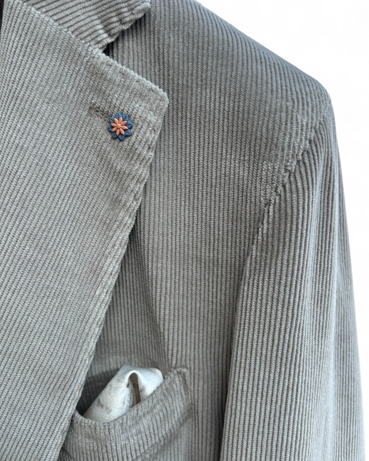 Dettaglio del rever della giacca Bharnaba Lamitam in velluto beige con spilla floreale e pochette, perfetta per look casual chic da uomo.