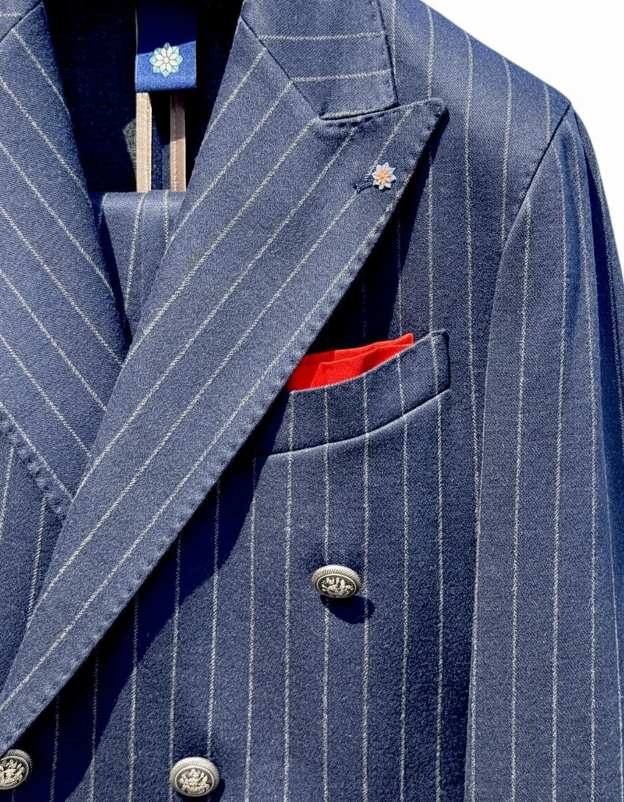 Primo piano dell'abito doppiopetto uomo elegante Aomori con righe gessate, bottoni decorativi e pochette rossa in contrasto.