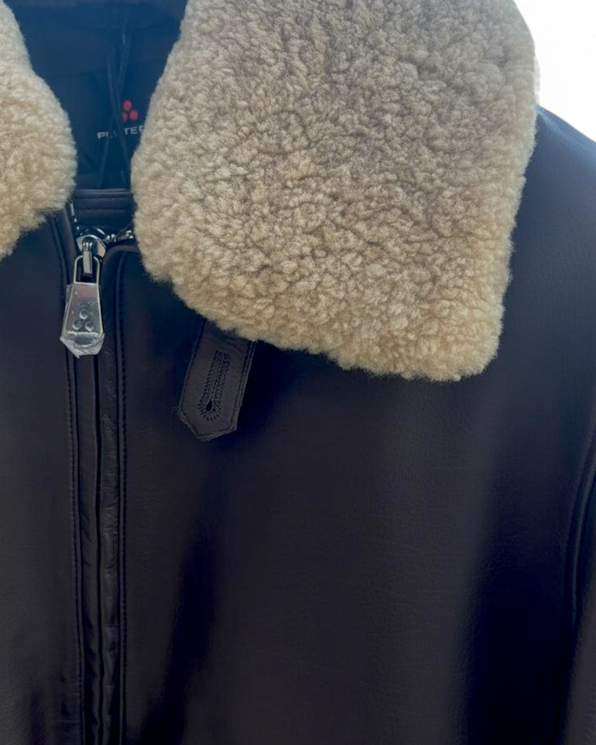 Dettaglio del collo shearling beige del giubbotto Murdo in pelle marrone, chiusura con zip e finiture di alta qualità per protezione dal freddo.