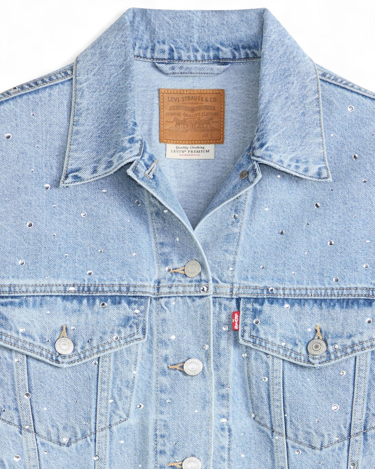 Dettaglio del colletto e delle tasche del Giubbino Jeans Trucker Strass di Levi's, con strass brillanti e etichetta in pelle sul retro del colletto.