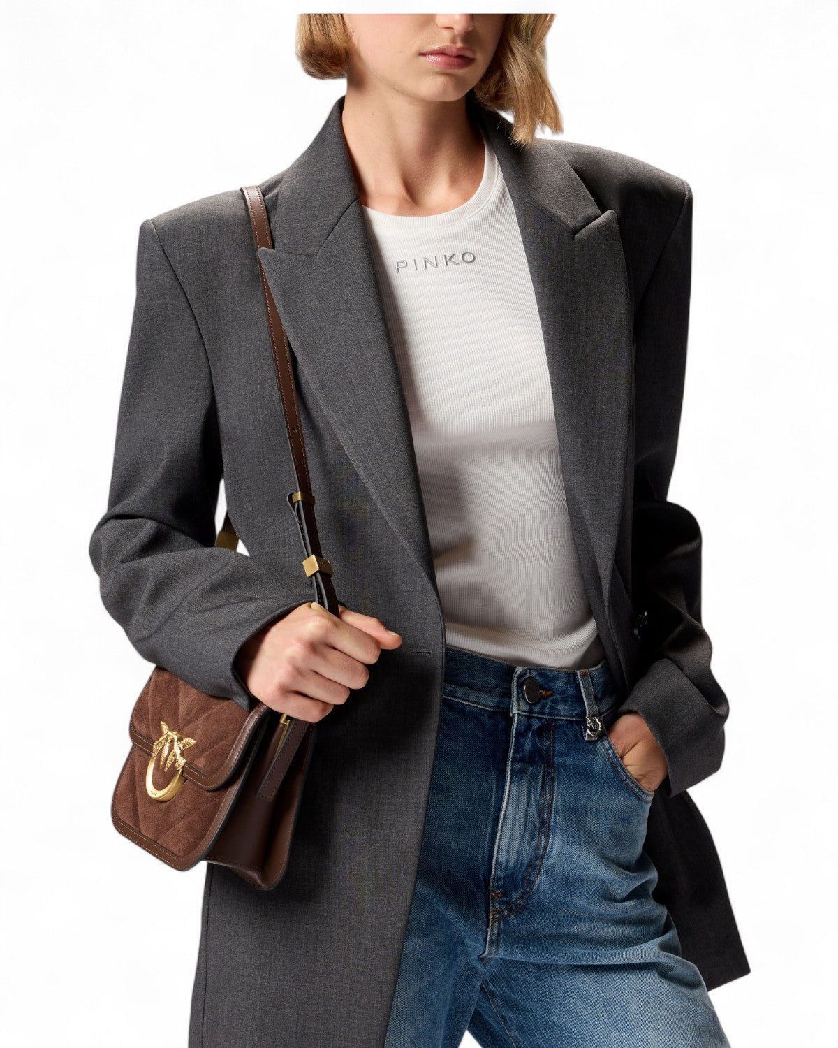 Dettaglio outfit con PINKO Mini Love Bag Box in pelle scamosciata marrone, indossata a spalla con blazer sartoriale e t-shirt bianca.